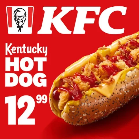 Hot dog z KFC z kurczakiem i sosem na czerwonym tle.