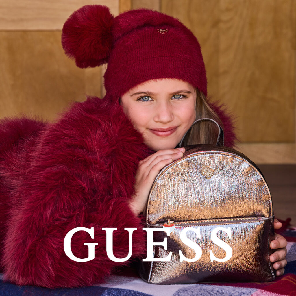 Dziecko w czerwonym stroju zimowym z plecakiem Guess.