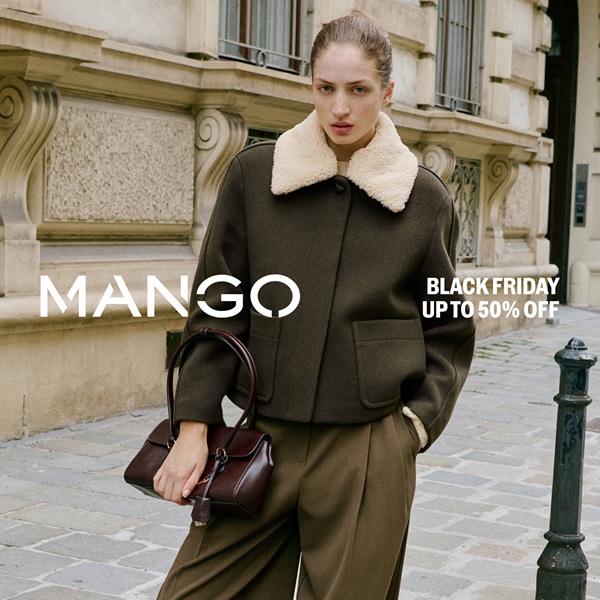 Kobieta w eleganckim płaszczu Mango na tle miejskiej architektury.