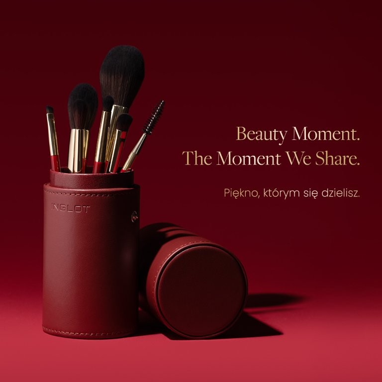 Zestaw pędzli do makijażu w eleganckim etui na czerwonym tle.