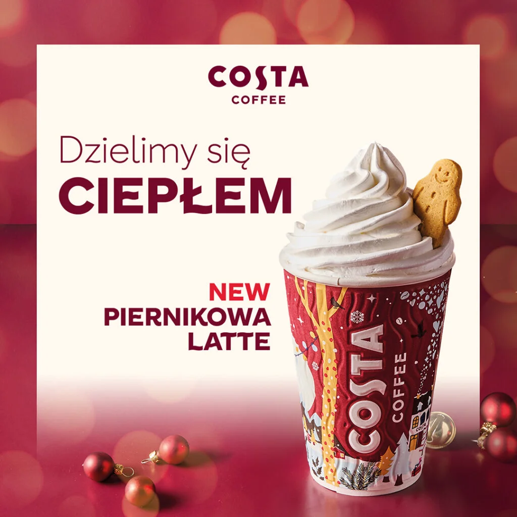 Kubek piernikowej latte z bitą śmietaną i pierniczkiem.