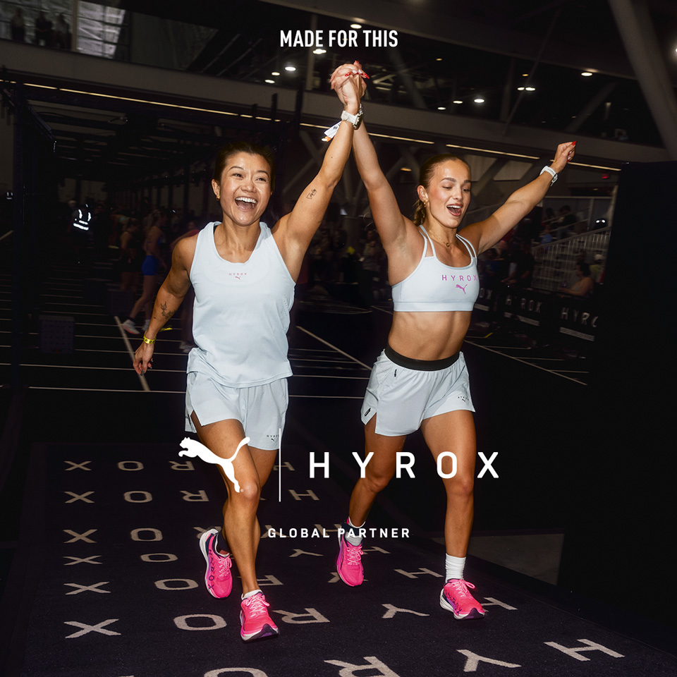 Dwie kobiety kończące bieg Hyrox, uśmiechnięte i trzymające się za ręce.