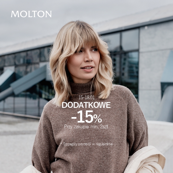 Kobieta w zimowym stroju przed nowoczesnym budynkiem.