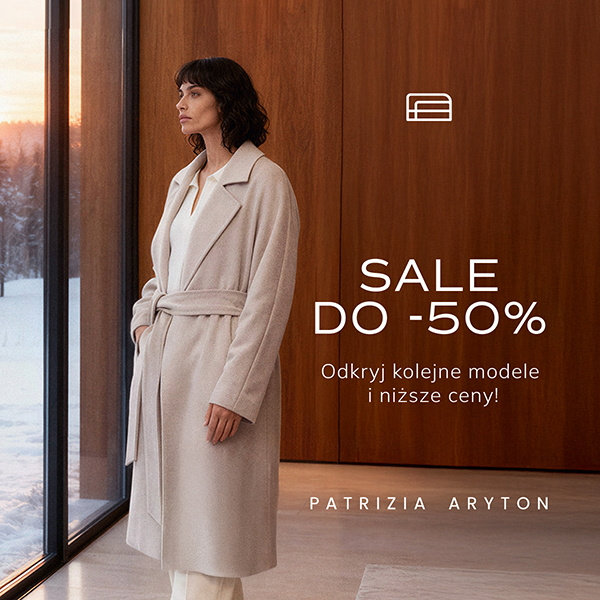 Kobieta w zimowym płaszczu patrzy przez okno.