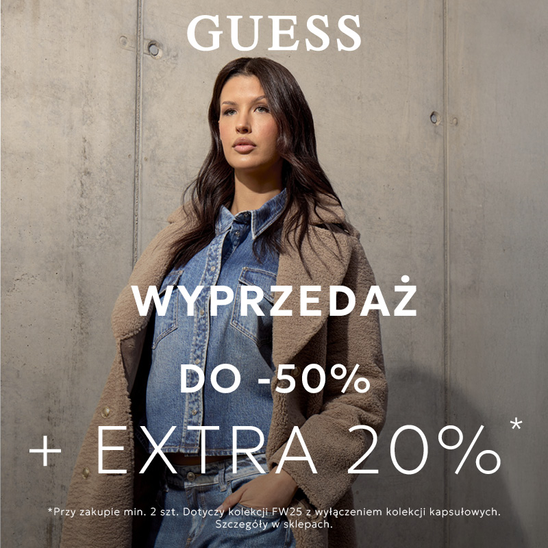 Modelka w ubraniach Guess na tle betonowej ściany, promocja do -50% i dodatkowe 20%.