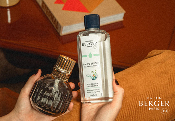 Osoba trzymająca lampę zapachową i butelkę płynu Maison Berger Paris.